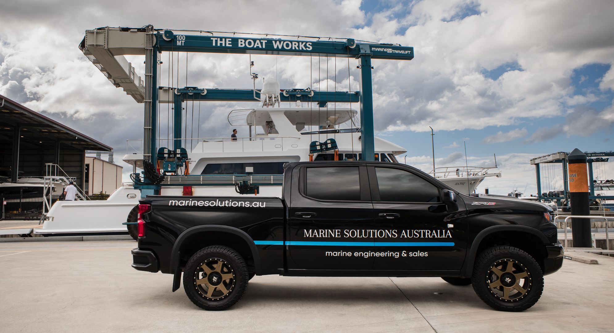 A Marine Solutions Australia vehicle in front of The Boat Works travel lift hoisting a motor yacht