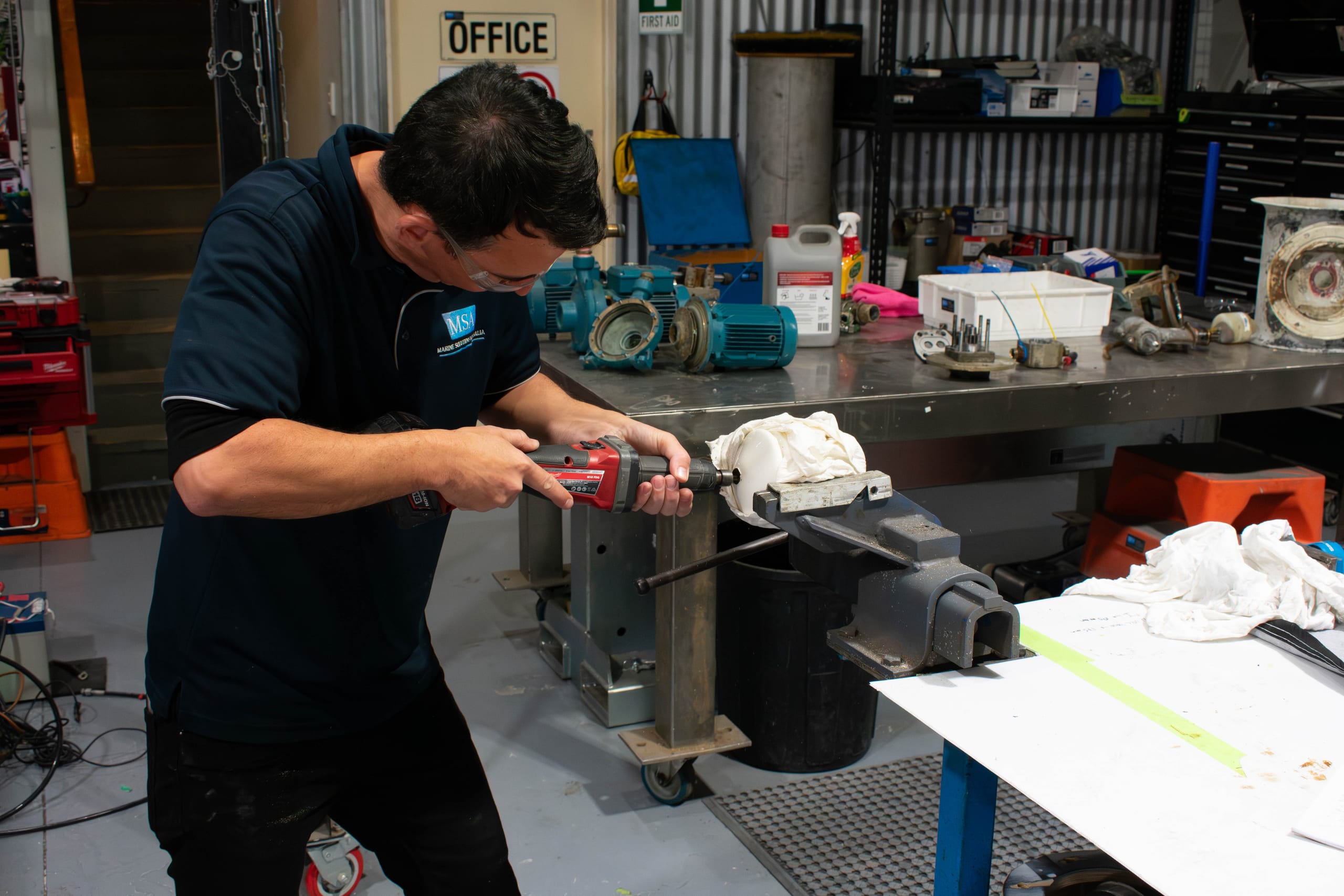 Marine Solutions Australia engineer precision-finishing a davit component held in a workshop vice