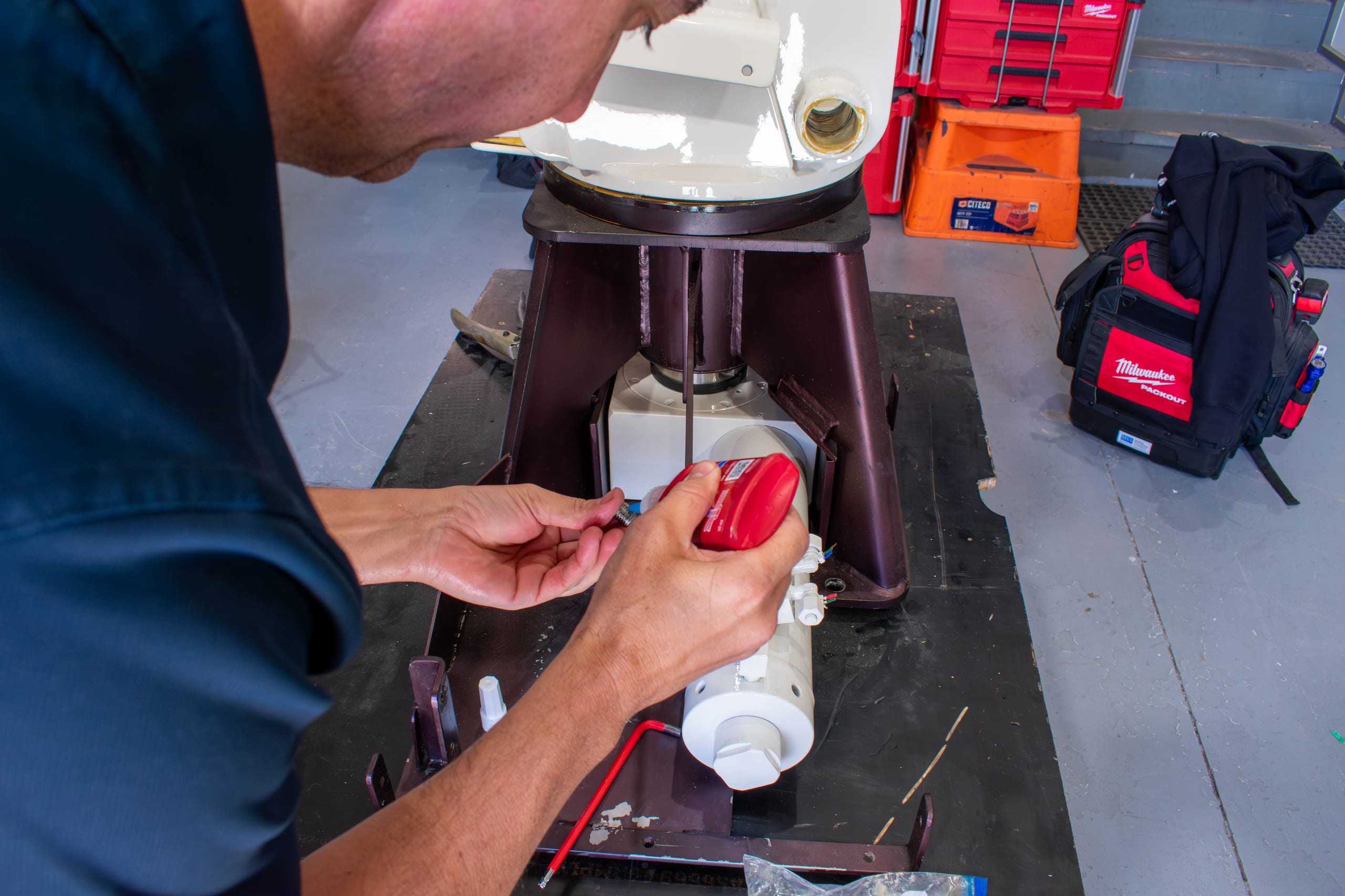 Technician applying threadlocker to a hydraulic cylinder fitting during a davit crane rebuild