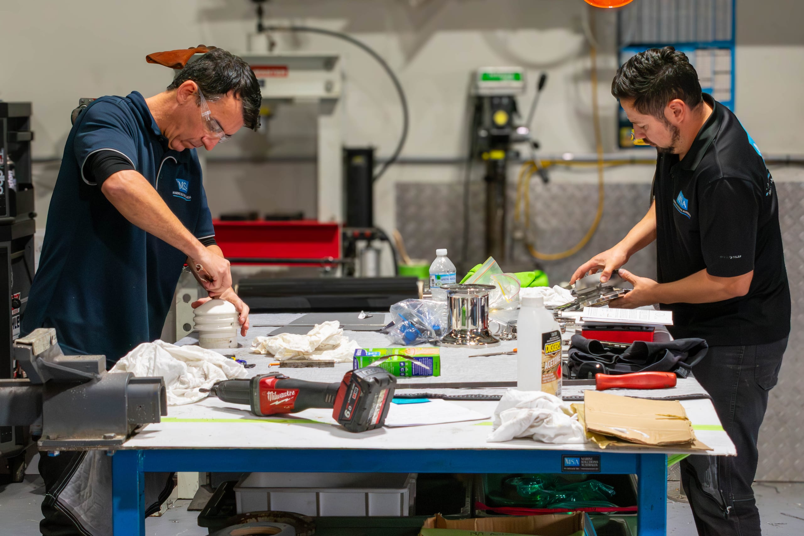 Two Marine Solutions Australia engineers working on davit components in the Coomera workshop