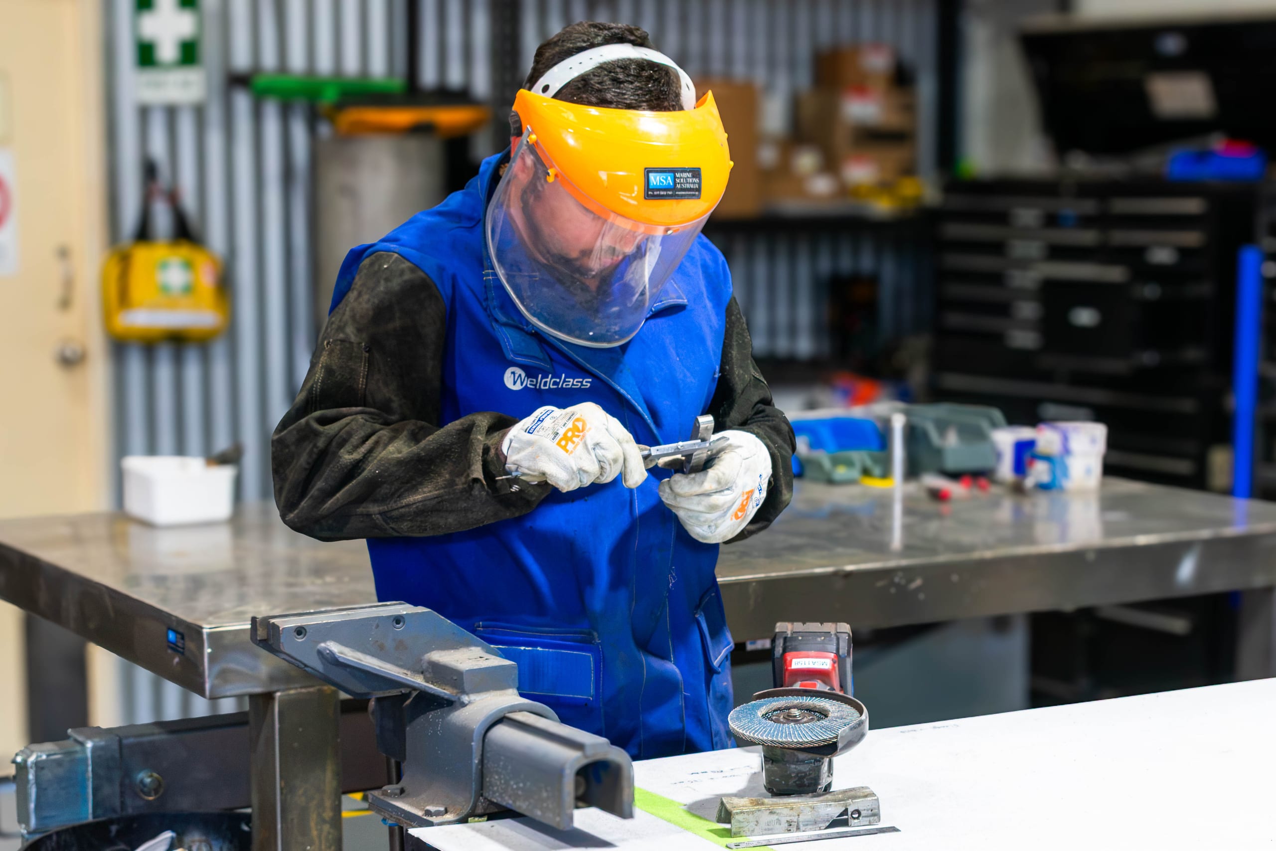 Marine Solutions Australia technician measuring a stainless steel part with a vernier caliper at the Coomera workshop bench