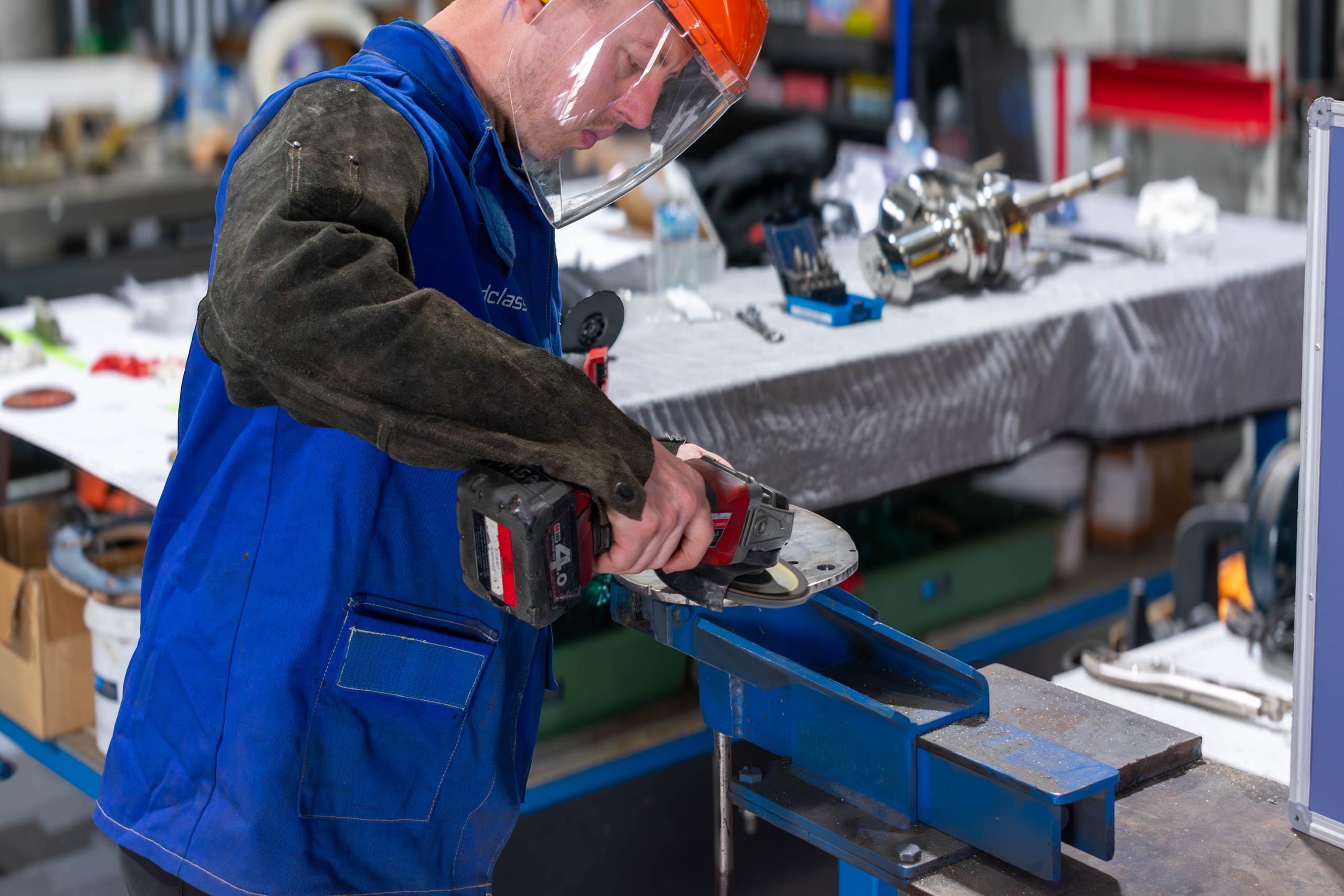 Marine Solutions Australia technician grinding a stainless steel flange held in a bench vice at the Coomera workshop