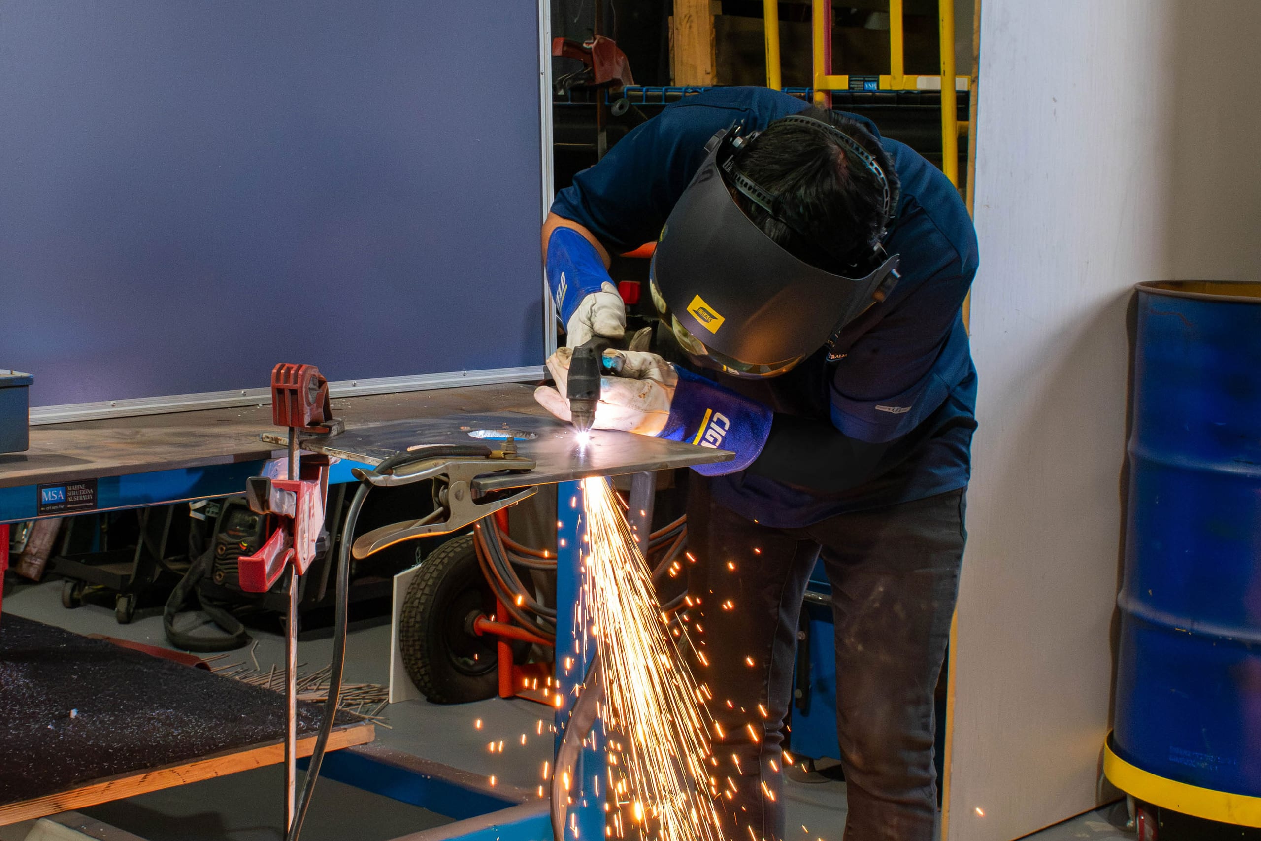 Marine Solutions Australia technician plasma cutting a stainless steel plate at the Coomera workshop bench