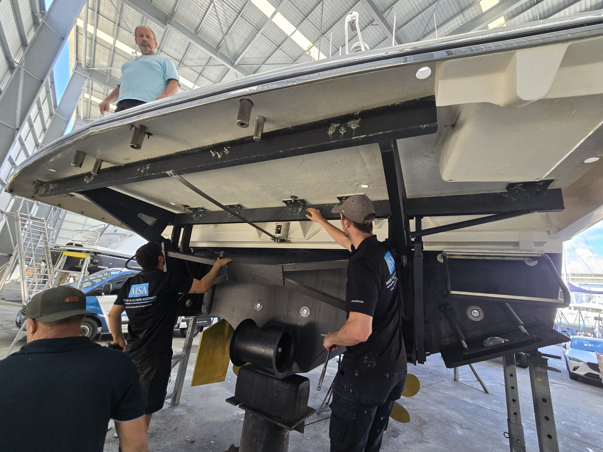 Marine Solutions Australia technicians working under the stern of a motor yacht on the hardstand