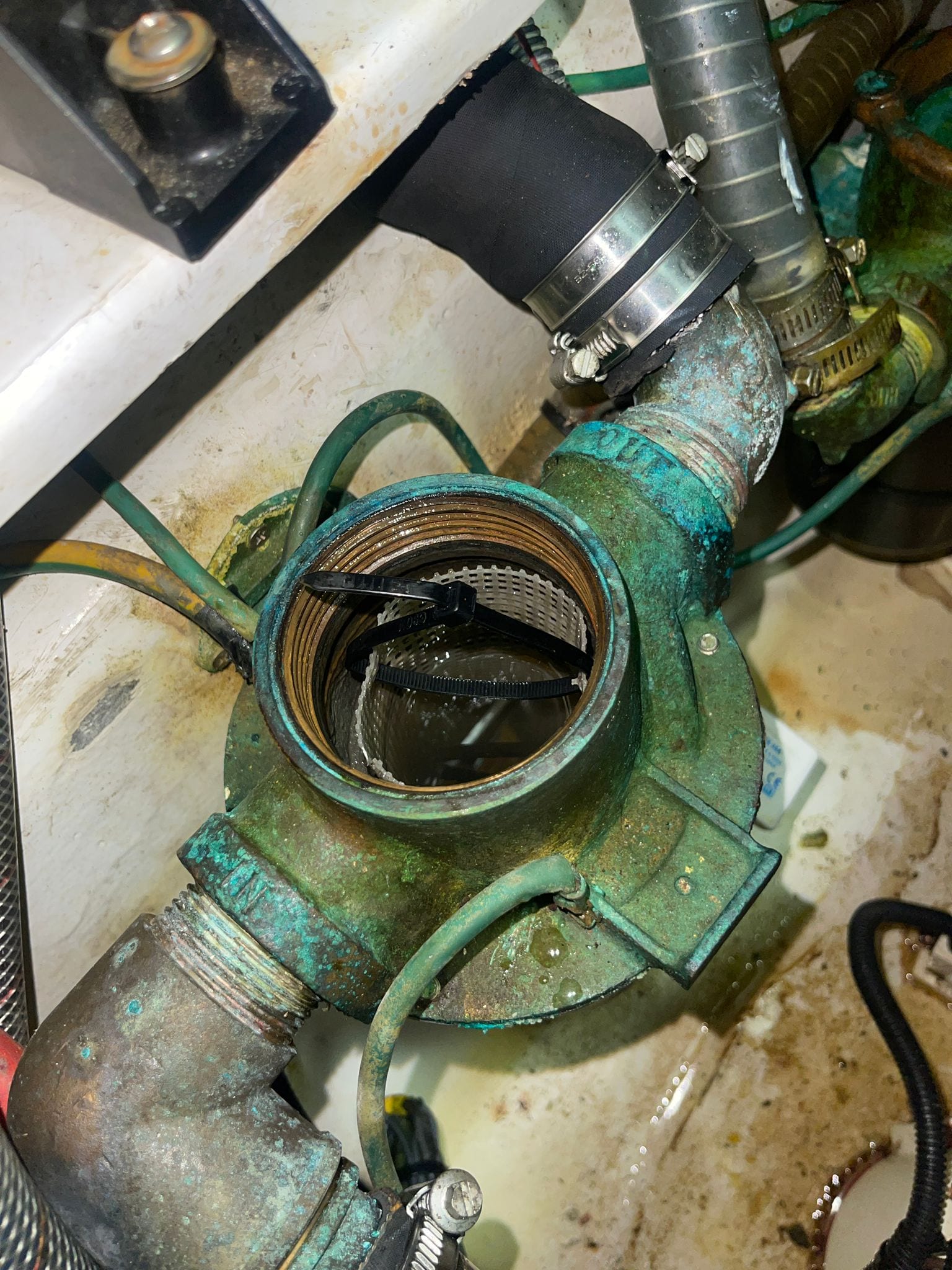 Sea strainer opened for inspection, verdigris through the bronze housing